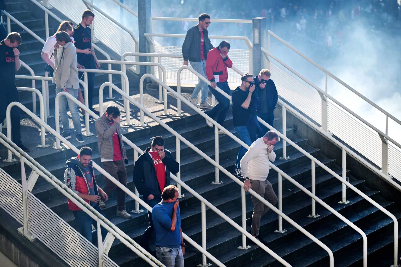 Fan covering their faces after tear gas used after Ajax-Feyenoord was abandoned (Photo: OLAF KRAAK/ANP/AFP via Getty Images)